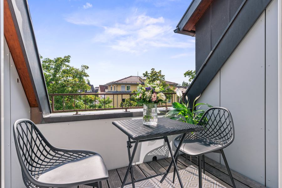Dachterrasse mit Tisch und zwei Stühlen, Blick über die Dächer