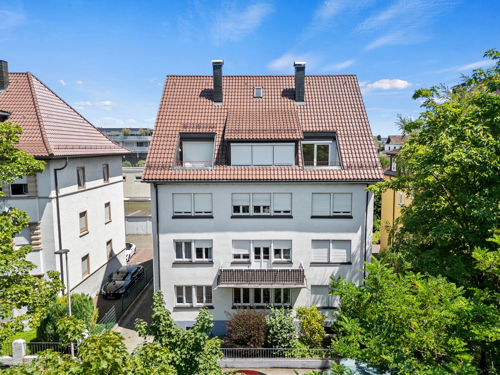 Riedleparkstraße 36 von oben: weißes Mehrfamilienhaus mit Ziegeldach und Gauben zwischen Bäumen