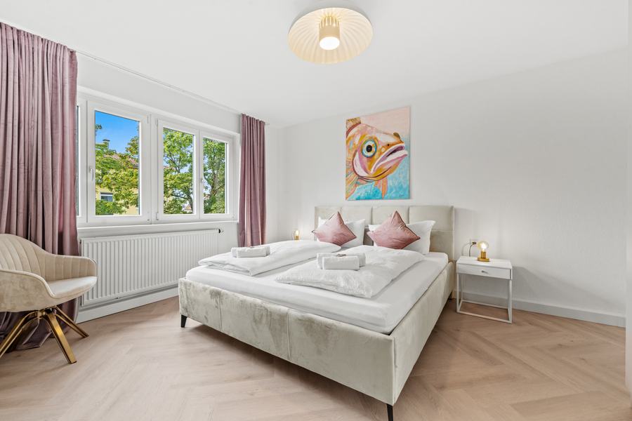 Schlafzimmer mit Doppelbett, Fischgrätboden und Fenster zum Garten